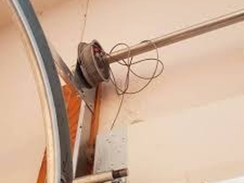 Close view of a frayed garage-door cable beside lifting hardware