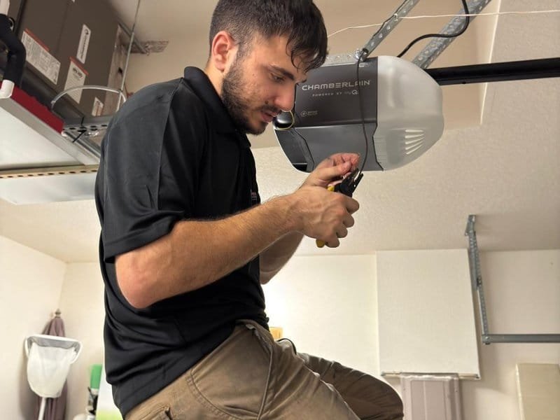Technician reaching an overhead garage-door opener motor and rail